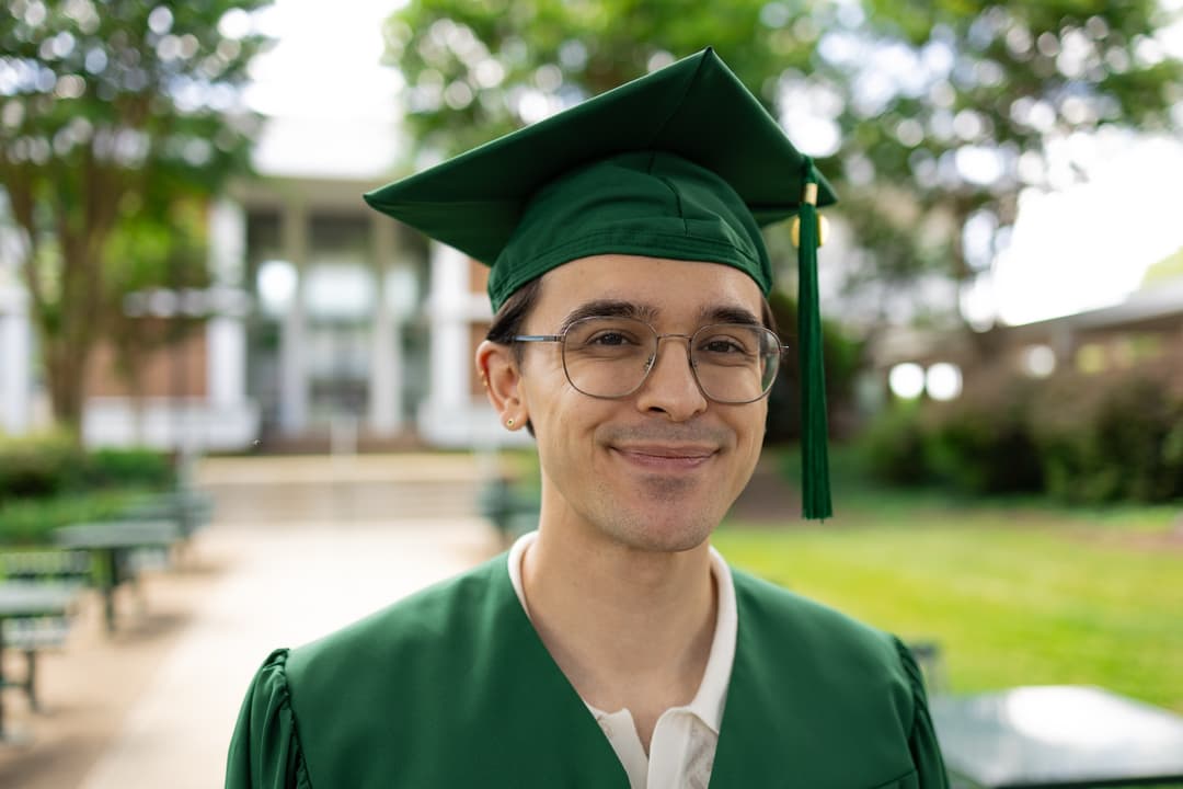 Picture of a grad in cap and gown, smiling